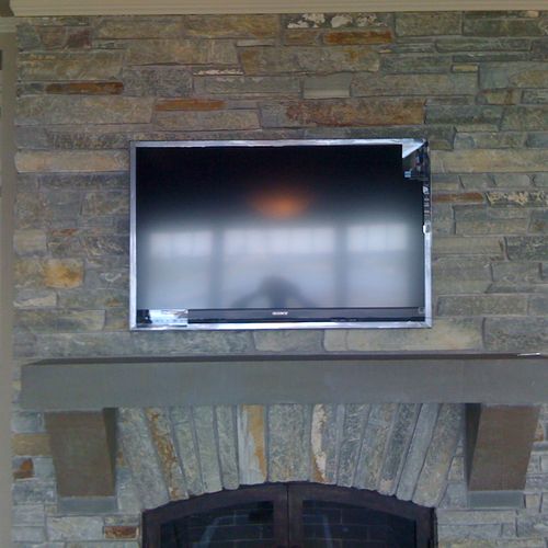 46" LCD mounted over a fireplace on a rock surface