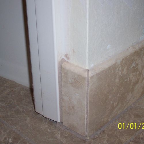 Mitered travertine trim tile with marble field til