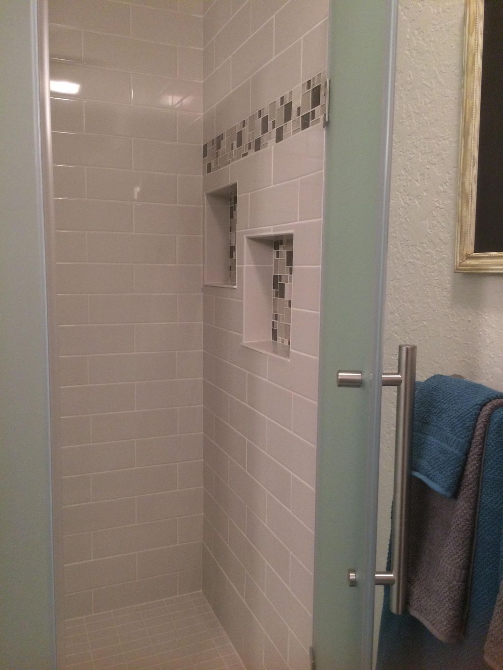 Custom tiled shower with glass door, shampoo niche