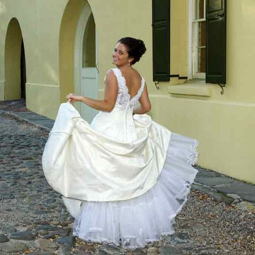 Cute bride strolls cobblestone road in Charleston,