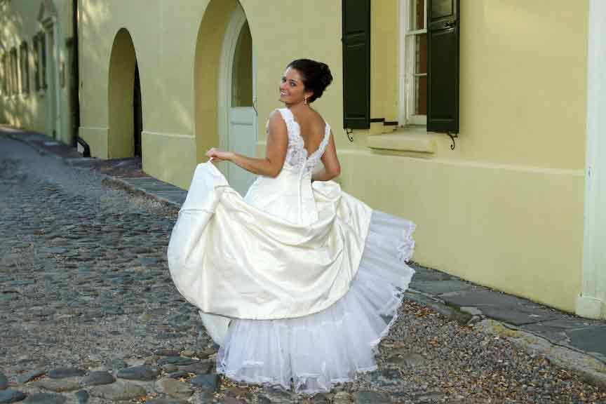 Cute bride strolls cobblestone road in Charleston,