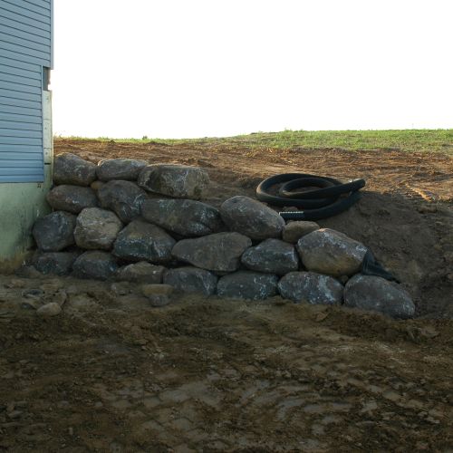 Boulder retaining wall to create walk-out area for