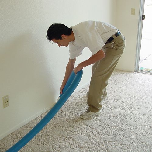 Vacuuming the edges where carpet meets wall.