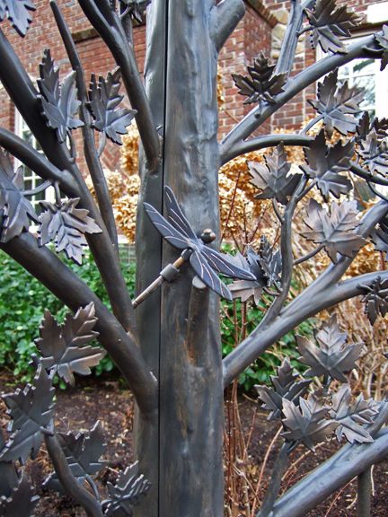 A dragonfly latch rests on the bark-textured gate 
