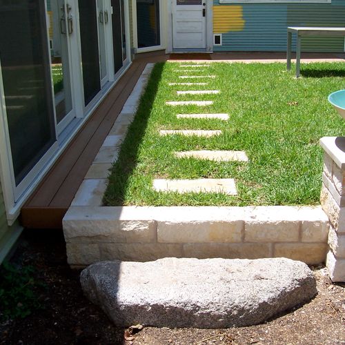 Stepping stones and wall amongst grass outside of 