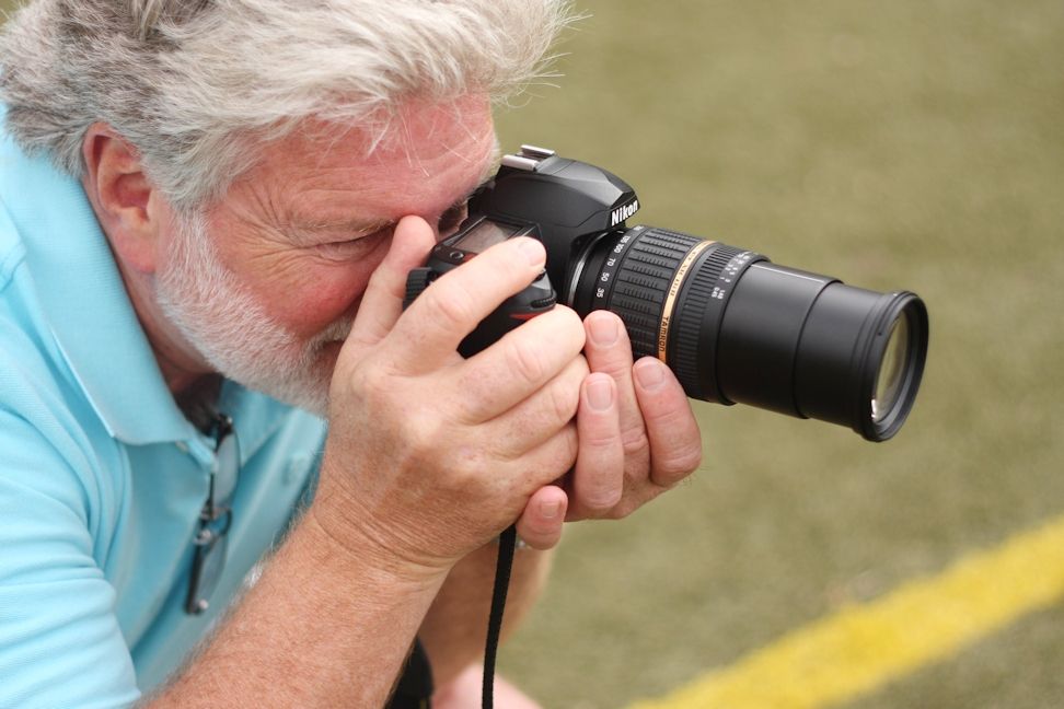A man learning to take pictures of sports.