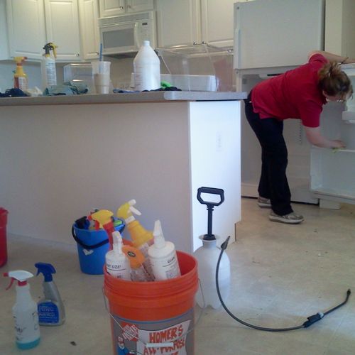 An employee cleaning a fridge in during a move out
