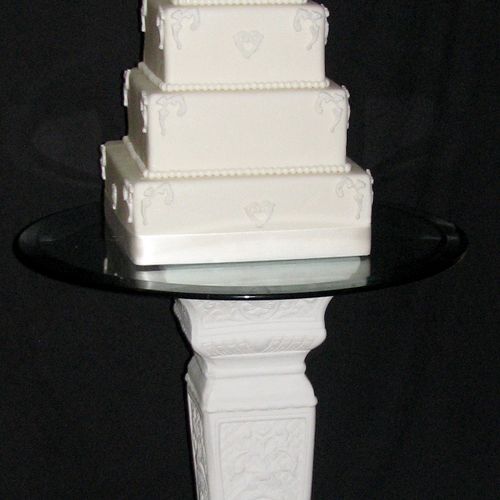Tiered wedding cake with fondant design and pedest