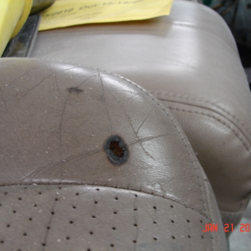 A before picture of a burn hole in a leather seat.