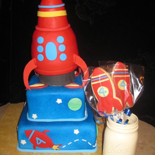 Rocketship themed birthday cake and cookie favors.