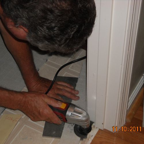 Cutting a door jam to install tile.