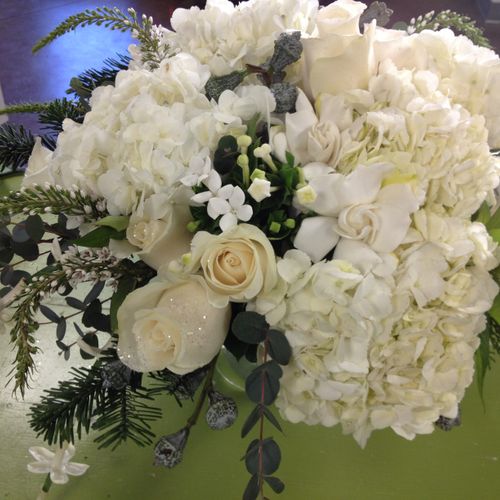 An all-white centerpiece with hydrangea, roses, ve
