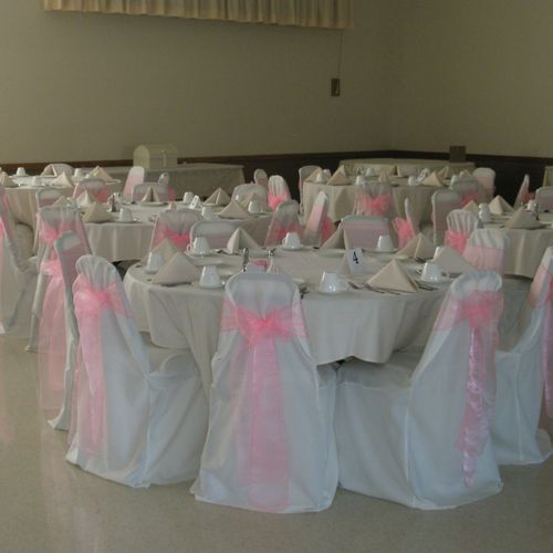 Ivory banquet chair covers wit pink organza sash.