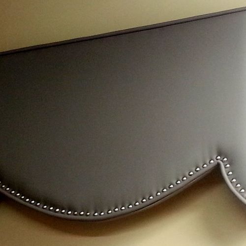 A faux leather upholstered cornice with decorative