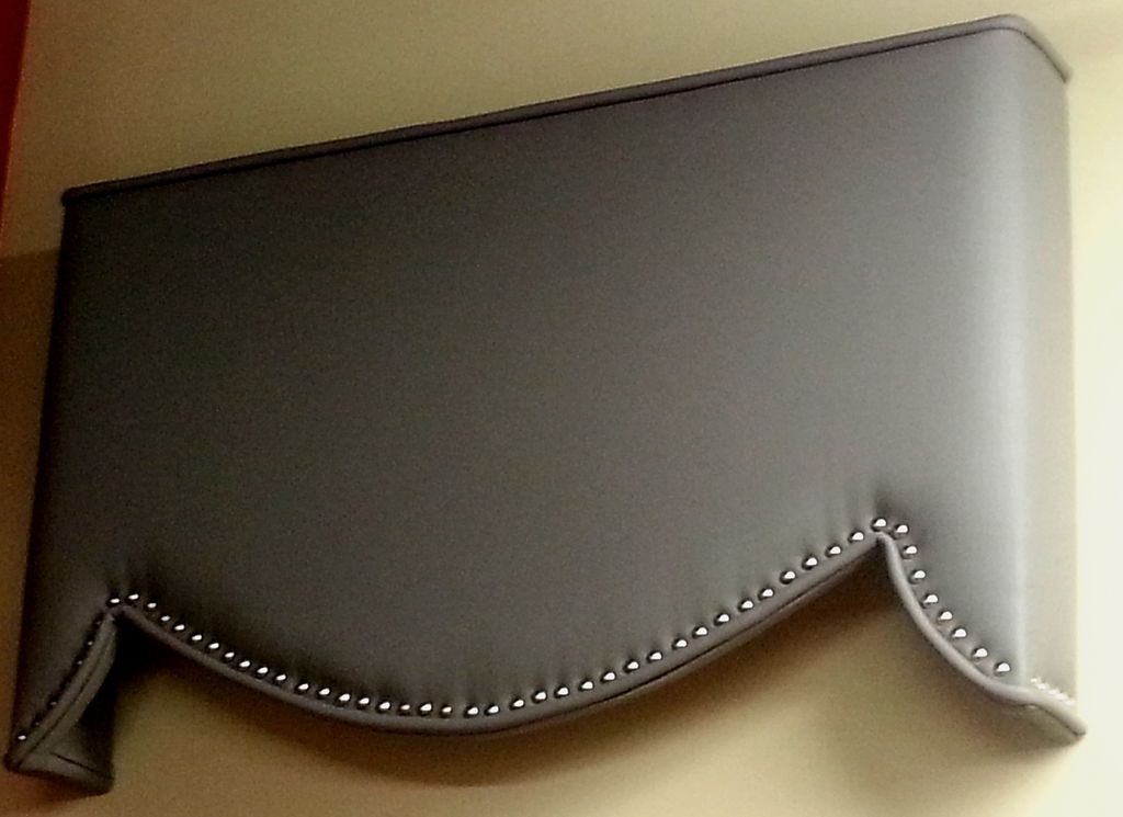 A faux leather upholstered cornice with decorative