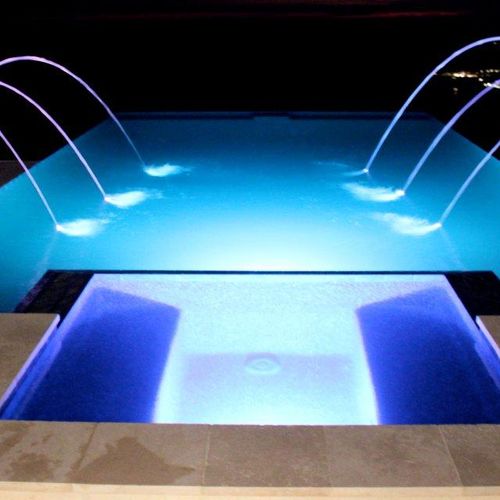Contemporary pool and spa at night with laminar de