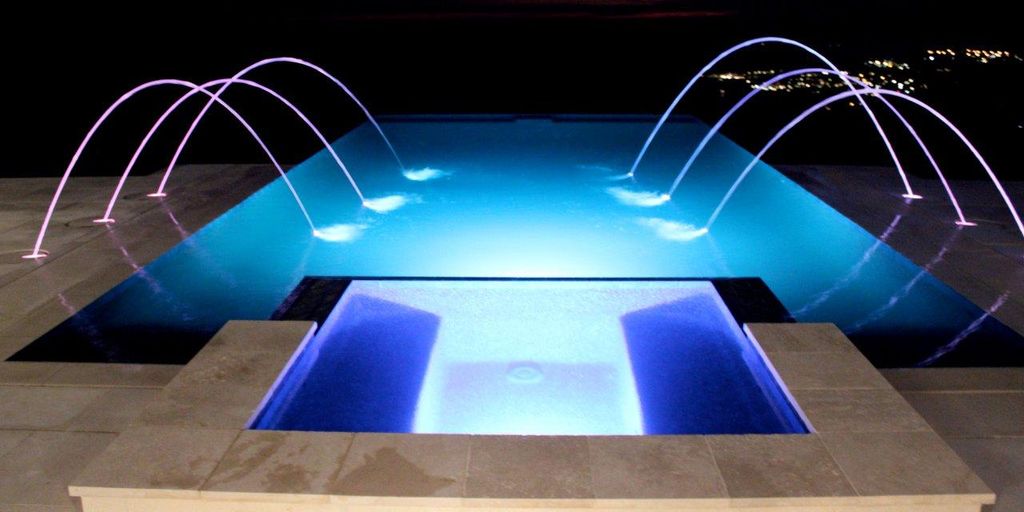Contemporary pool and spa at night with laminar de