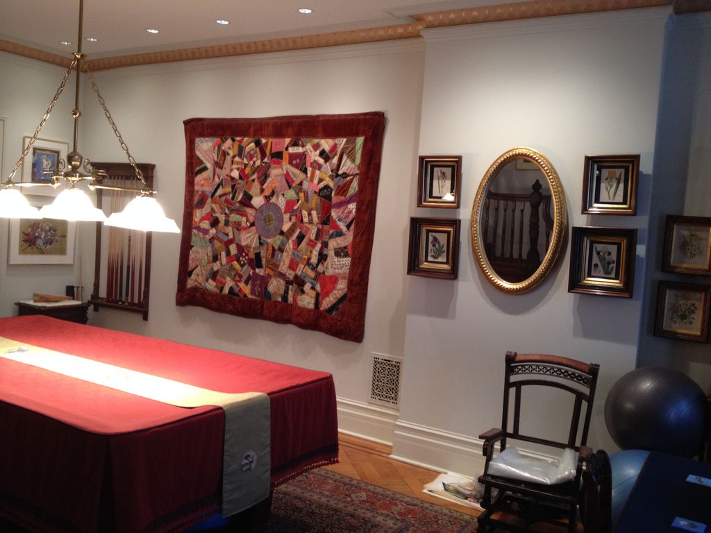 Antique quilt and artwork hung on plaster/brick wa