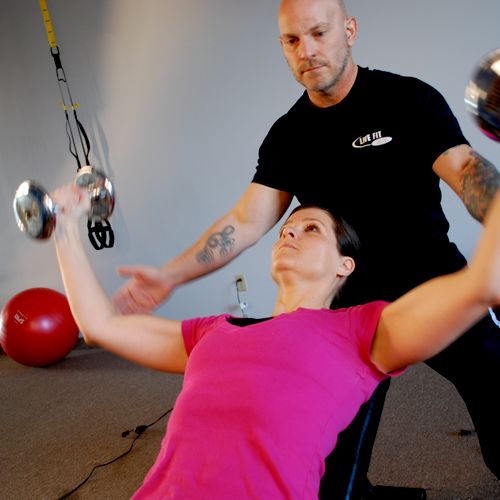 Tom helping a client with her weight lifting techn