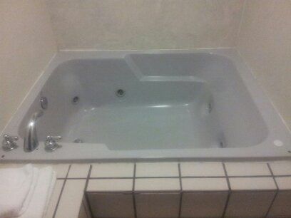 A 4 person hot tub with ceramic tile surrounding i