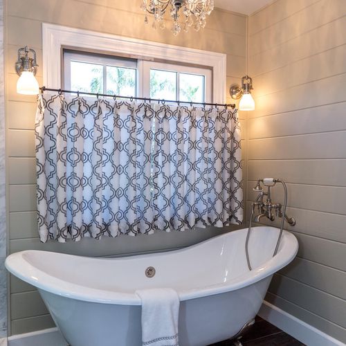 Claw-foot tub with cafe curtain, crystal chandelie