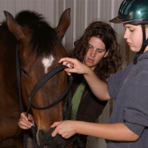Me helping a student tack up a horse
