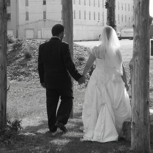 June wedding: Bride and Groom walking under archwa