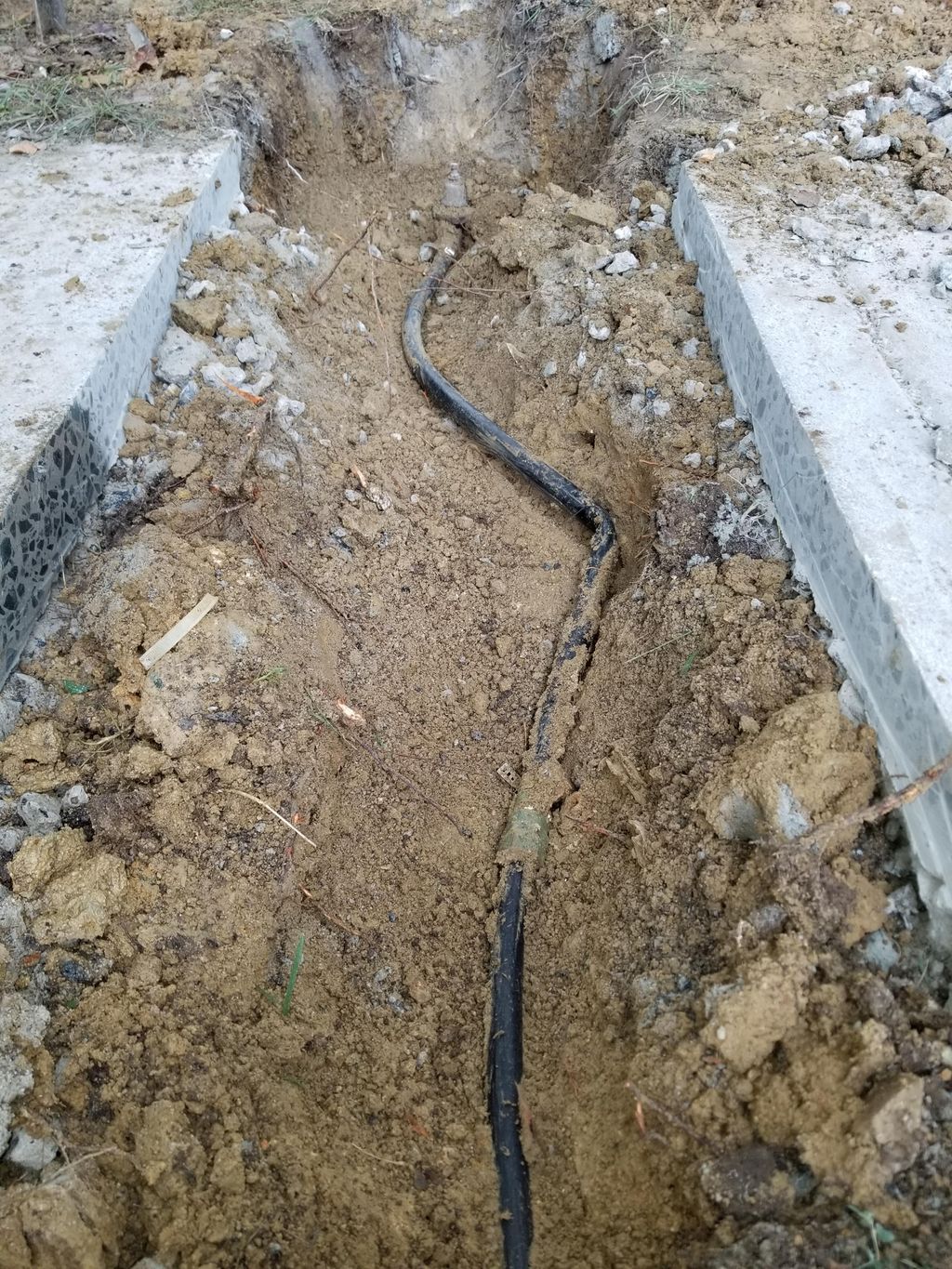 Kinked pipe split under sidewalk (before repair)