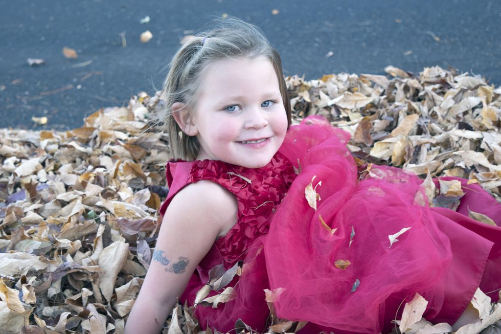 Little girl posing in a pile of leaves during phot