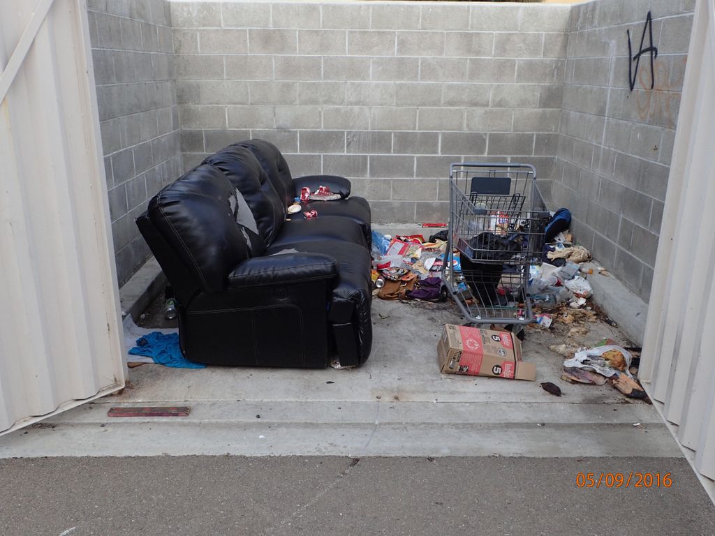 Trash people left behind in a dumpster enclosure.