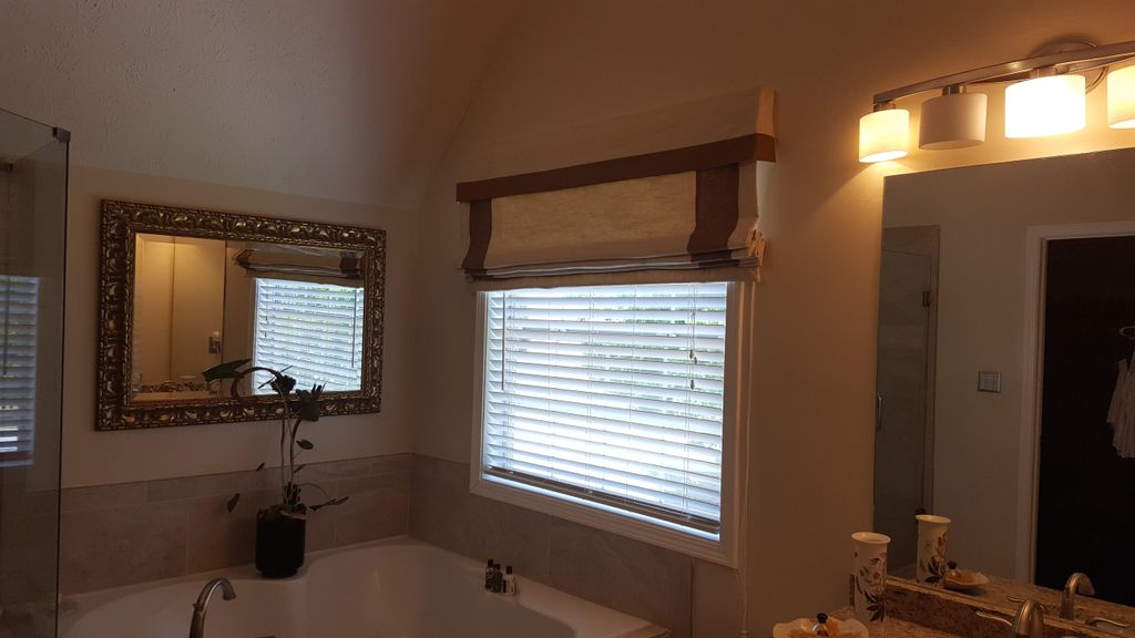 A banded roman shade with attached valance in bath