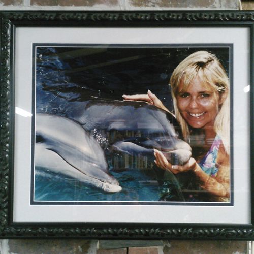 Matted and framed photo of lady with the dolphins