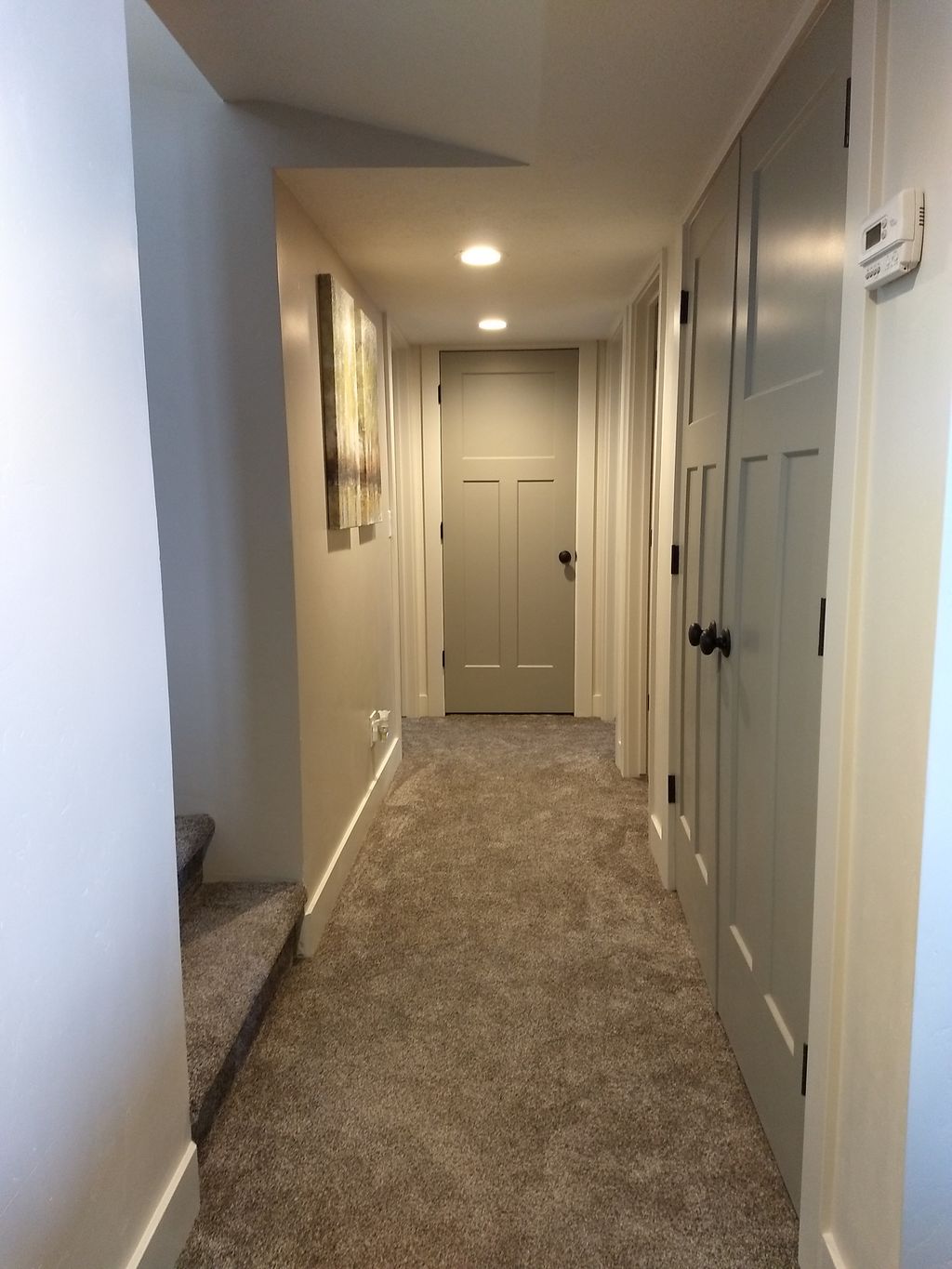 Basement hallway with case around doors and base.