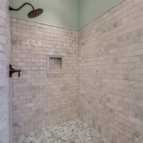 Custom showers with marble tile and pebble floor