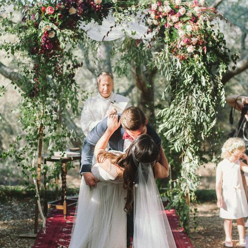 Ceremony under oak trees with a natural arch and r