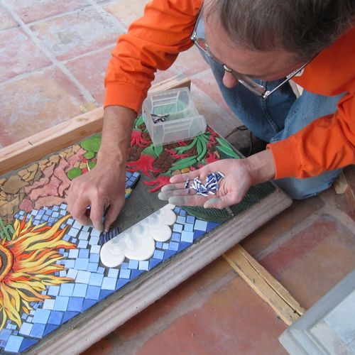 Installing hundreds of tiles into mosaic on garden