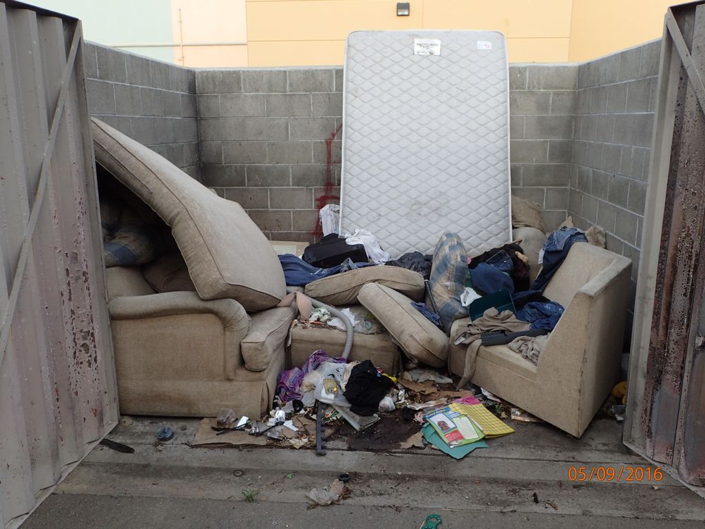 Trash people left behind in a dumpster enclosure.