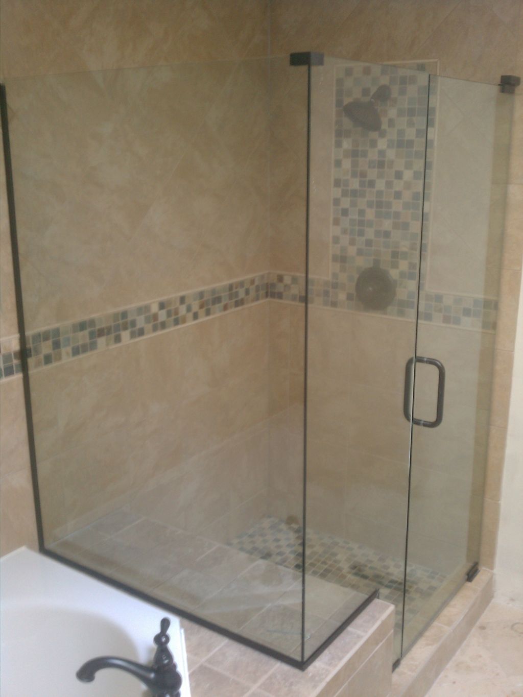 Corner shower on the end of a bathtub. 