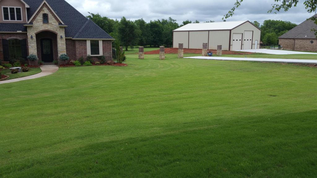 Sod, concrete driveway, and stone pillars by M&V G