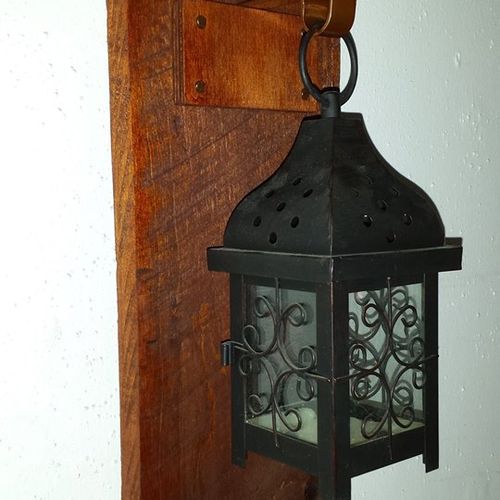 Wall lantern made with a pallet slat and hook.