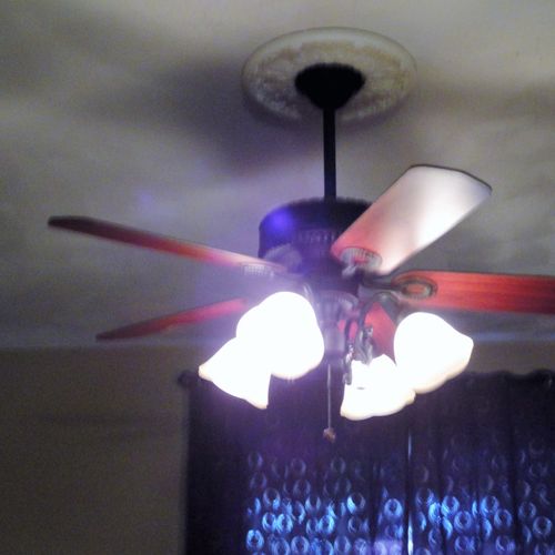 A ceiling fan installed with a medallion in a livi