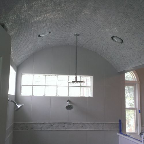 all white tile and an arched ceiling with mosaic t