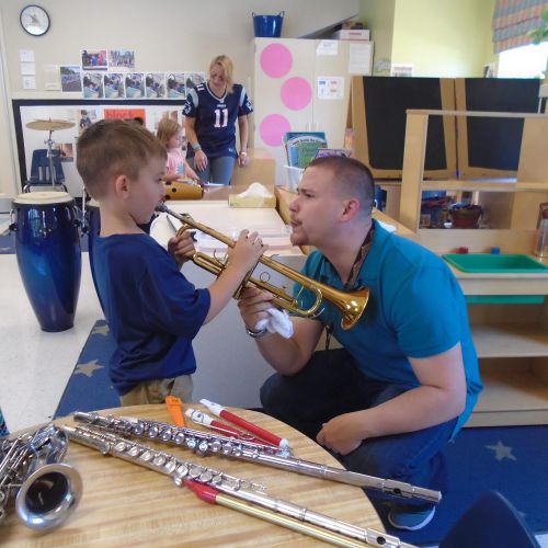Showing a child how to buzz on a trumpet mouthpiec