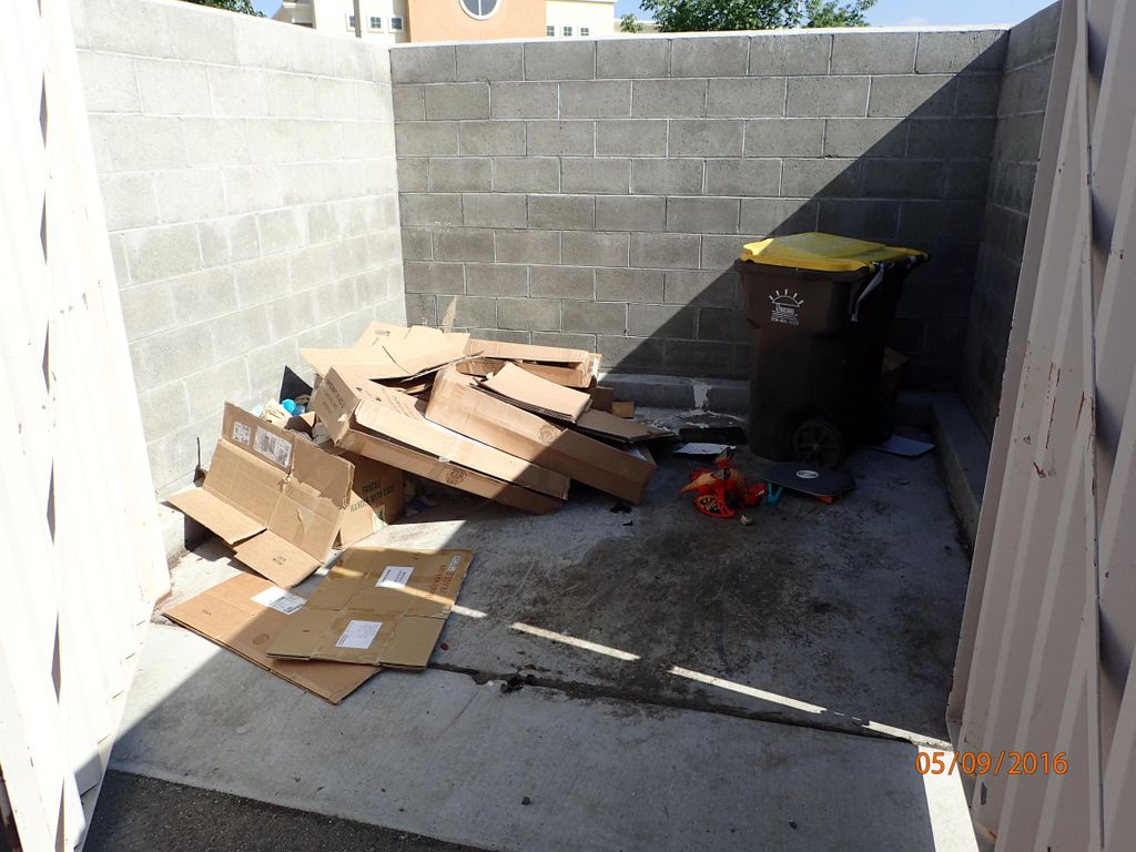 Trash people left behind in a dumpster enclosure.