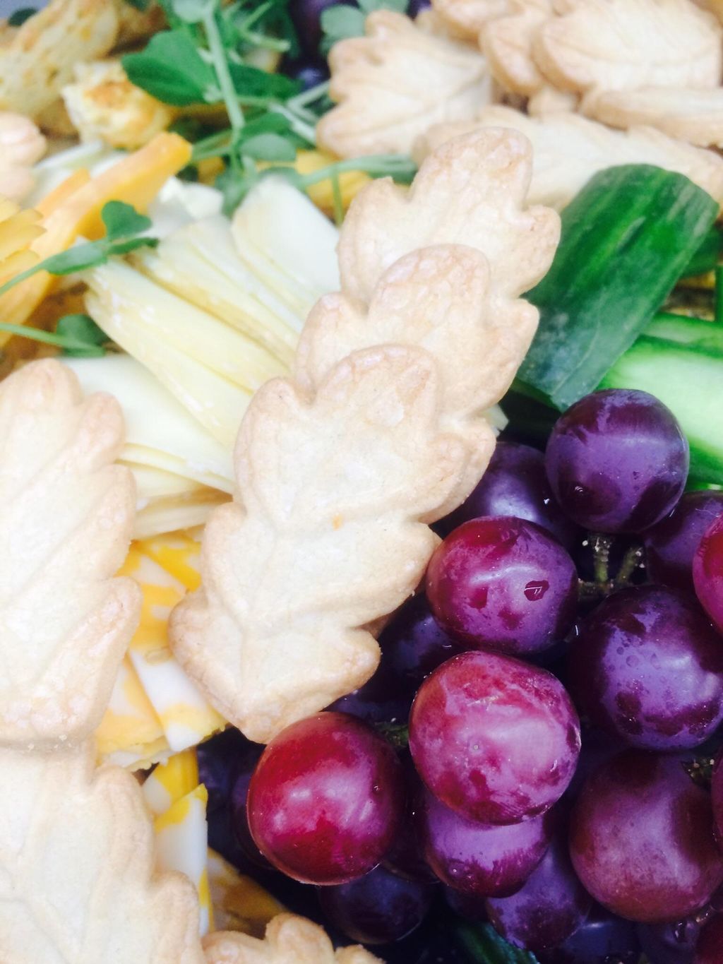 Grapes butter cookies cucumbers and cheese served 
