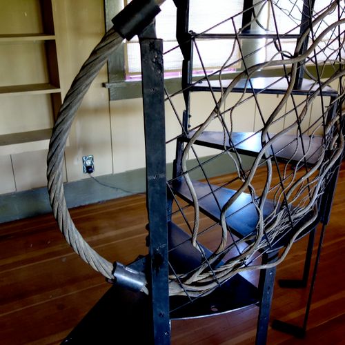 Blackened steel spiral staircase and wire rope rai