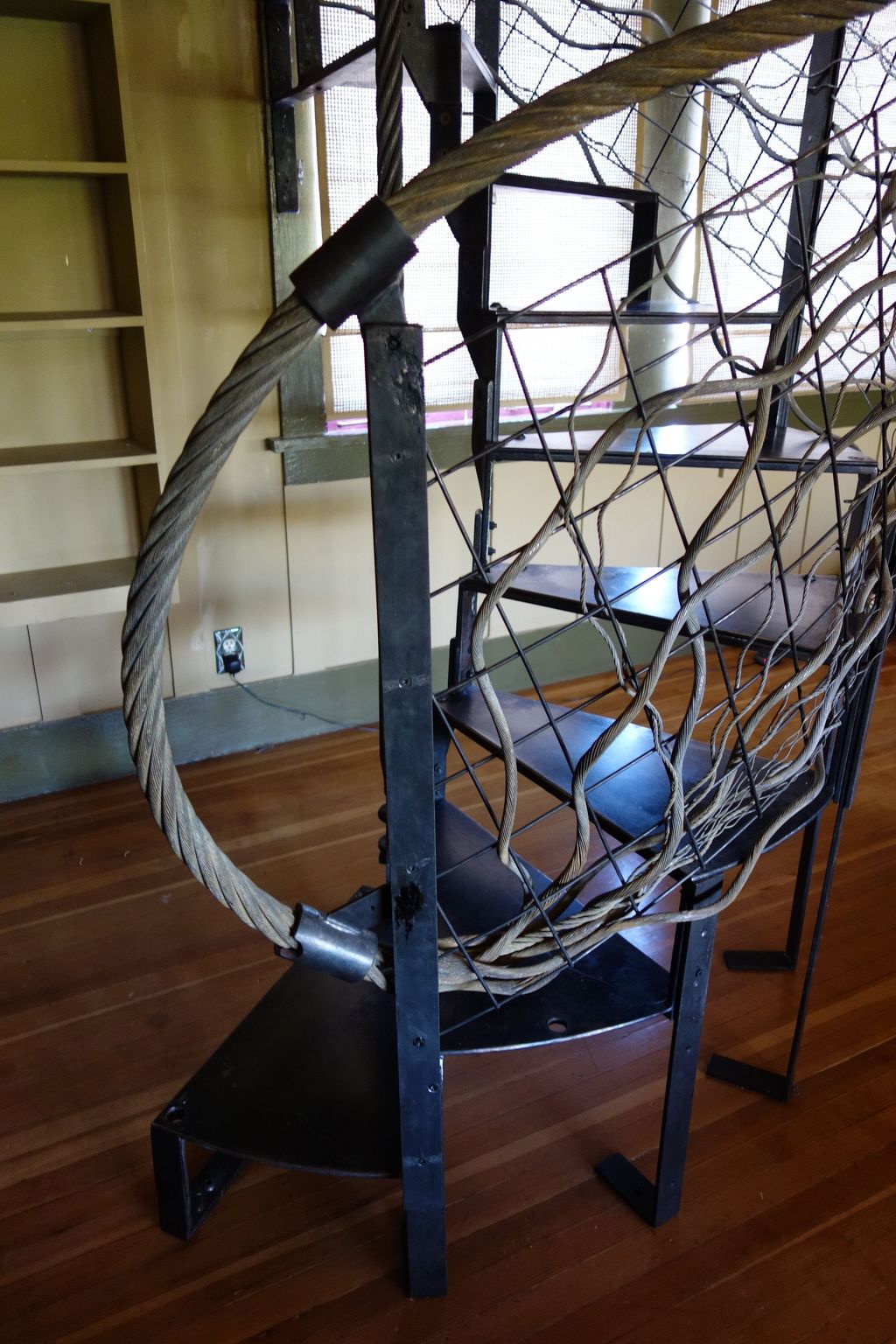 Blackened steel spiral staircase and wire rope rai