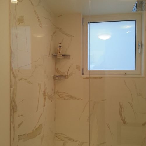 Porcelain walls and floors, walk in shower stall.