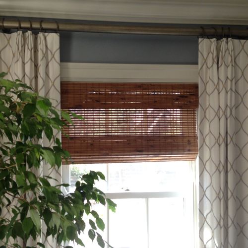 layers of drapery over woven wood shades for a bed