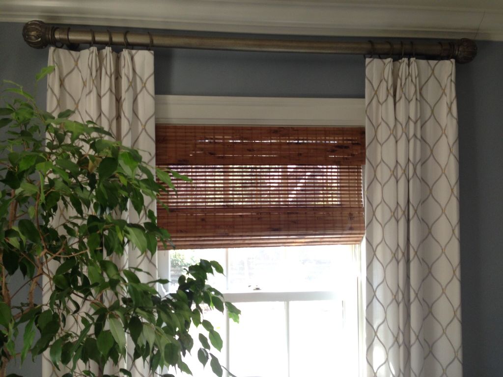 layers of drapery over woven wood shades for a bed